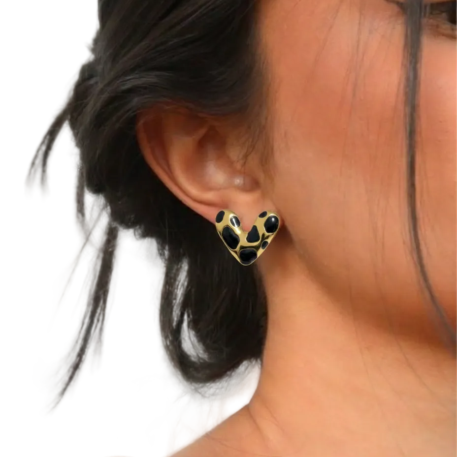 Close-up of an ear wearing a gold earring with black accents on a white background