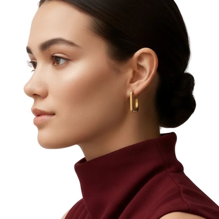 Woman wearing gold hoop earrings with a plain background